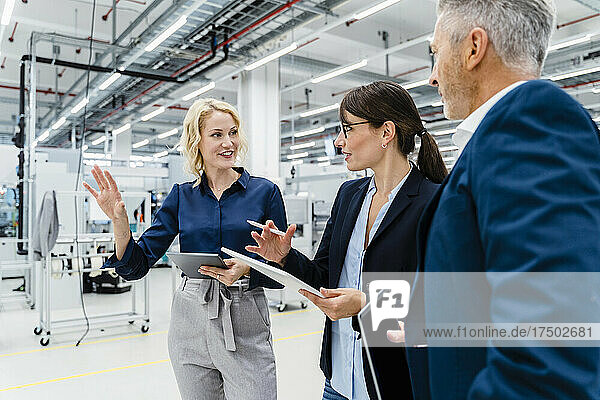 Businesswomen having discussion by businessman at automated factory