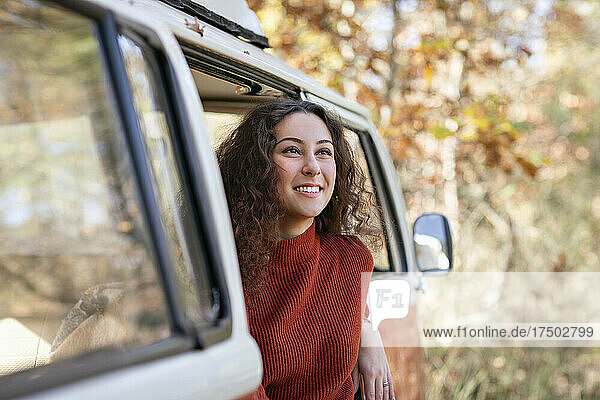 Lächelnde junge Frau schaut vom Wohnmobil weg