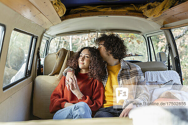 Young man kissing girlfriend in campervan