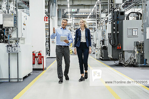 Businessman inspecting machinery with coworker in automated factory