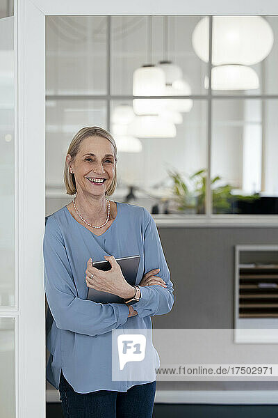 Businesswoman holding tablet PC at office doorway