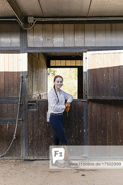 Smiling woman leaning on horse stable