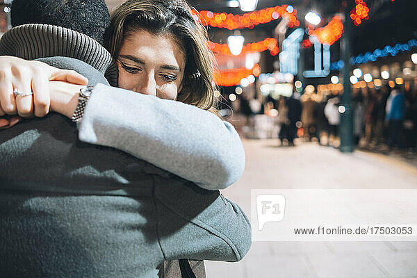 Couple embracing each other at illuminated Christmas market