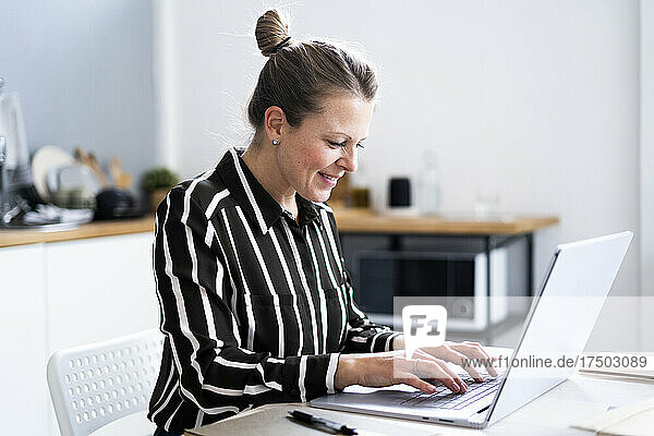 Smiling freelancer using laptop at home office