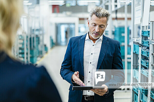 Businessman discussing over tablet PC with colleague at factory