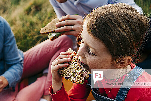 Mädchen isst Sandwich mit Eltern im Park