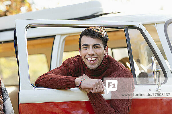 Happy young man leaning on door of van