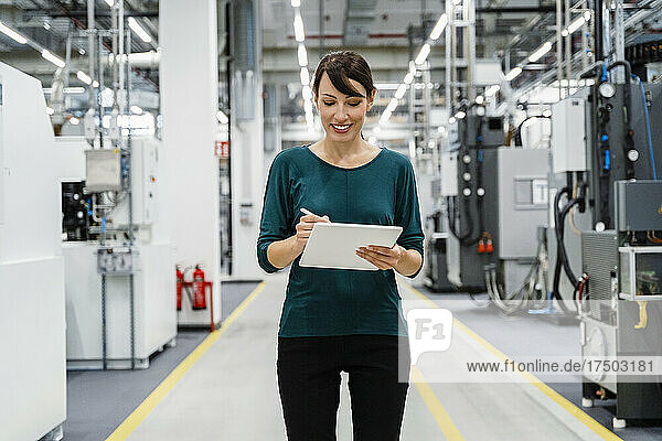 Smiling businesswoman using tablet PC in factory