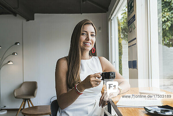 Schöne Frau hält eine Kaffeetasse und lächelt im Café