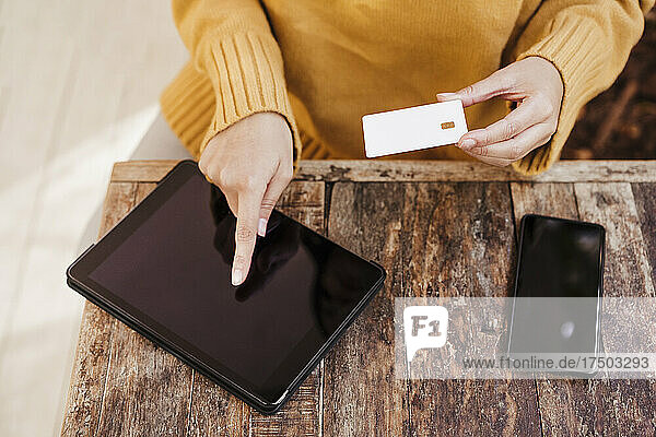 Frau kauft online über ein digitales Tablet am Cafétisch ein