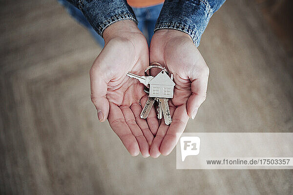 Woman with hands cupped holding house keys at home