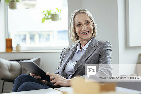 Smiling businesswoman holding tablet PC in office