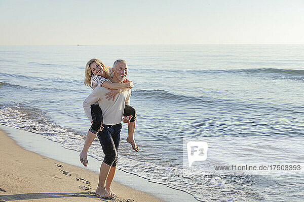 Man piggybacking woman near sea at beach