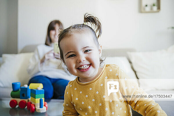 Happy baby girl with mother in background at home