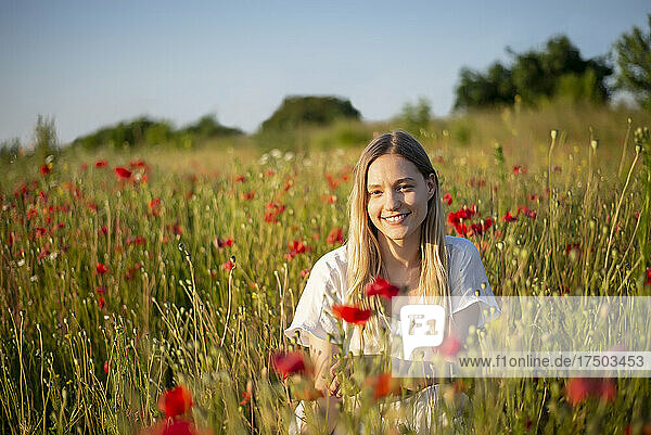 Lächelnde junge Frau im Mohnfeld