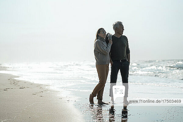 Tochter und Vater stehen an einem sonnigen Tag gemeinsam am Meeresufer