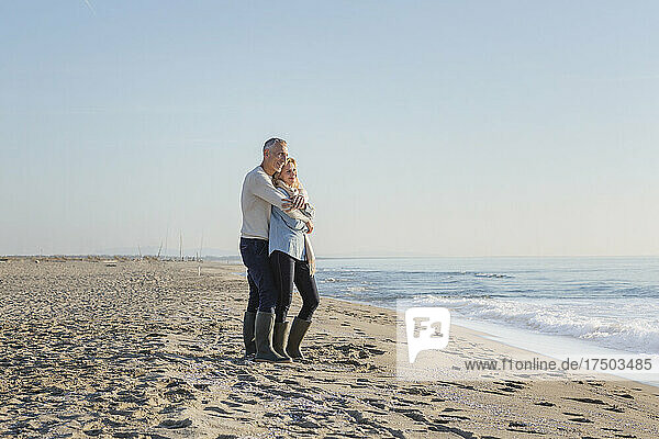 Couple embracing each other standing on sand at beach