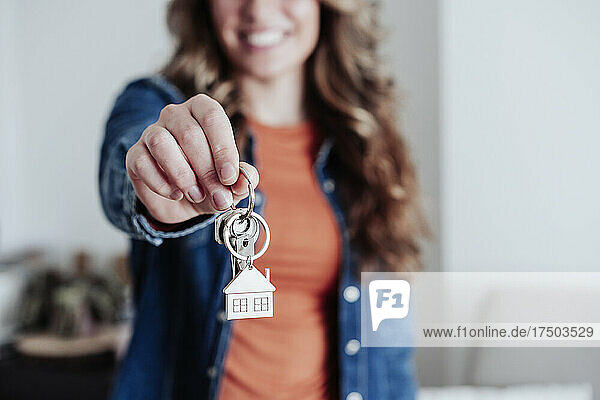 Junge Frau zeigt Hausschlüssel im neuen Zuhause