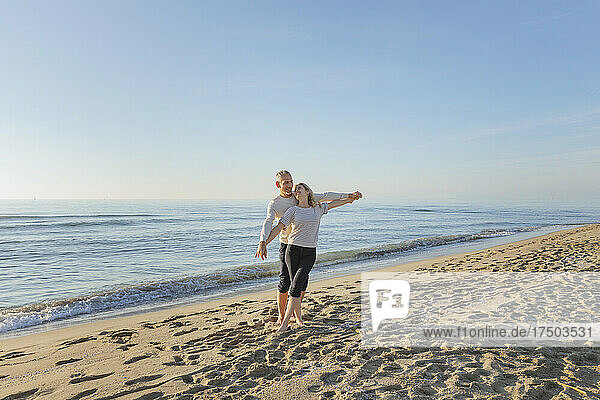 Romantic couple with arms outstretched standing at beach
