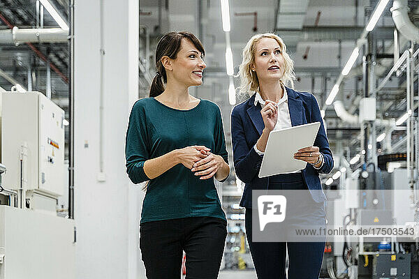 Businesswoman working with colleague in modern factory