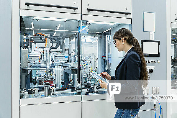 Inspector using tablet PC at industrial machinery