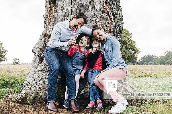Happy family enjoying lollipops near tree in park