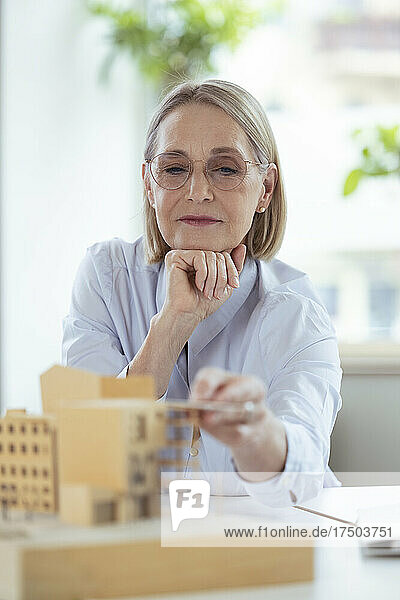 Female architect checking model at office desk