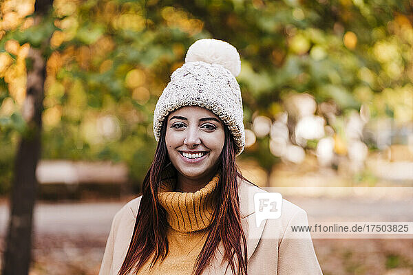 Young woman wearing knit hat at autumn park