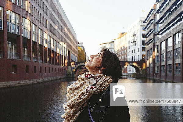 Thoughtful woman wearing scarf and jacket at canal