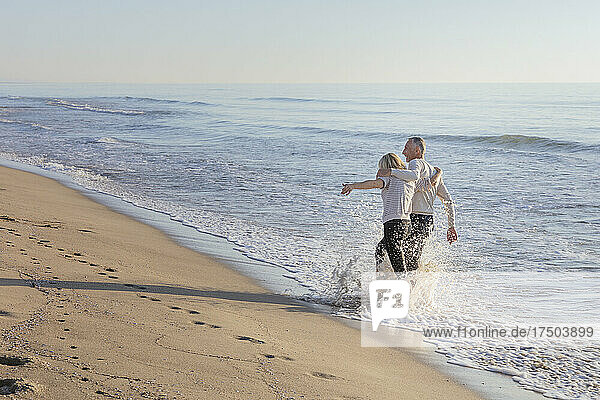 Paar bespritzt sich am Strand gegenseitig mit Wasser