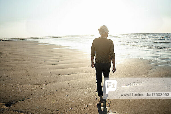 Senior man walking towards sea at beach