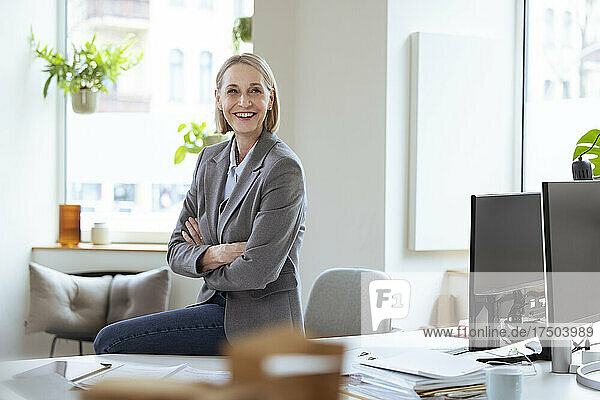 Smiling businesswoman with arms crossed in office