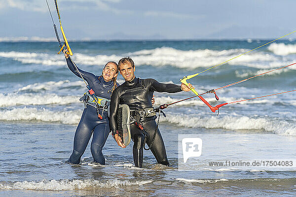 Smiling friends kitesurfing in water