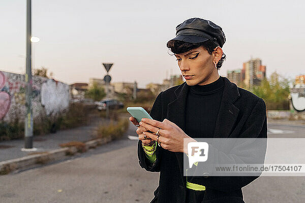 Gay man with cap using mobile phone on road