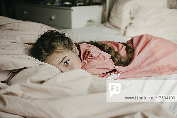 Girl with gray eyes lying on bed at home