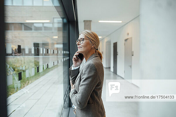 Businesswoman talking on mobile phone at office corridor