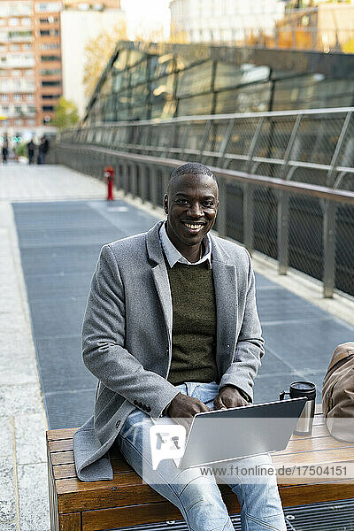Working man with laptop sitting on bench