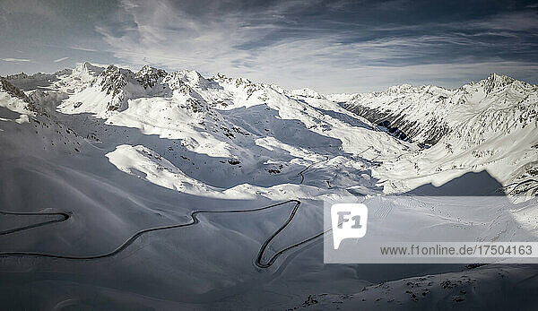Aerial view of winding road stretching across snowcapped Kaunertal valley at dusk