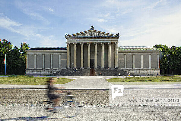 Deutschland  Bayern  München  Frau fährt Fahrrad am Museum der Staatlichen Antikensammlung vorbei