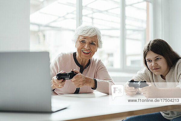 Senior woman playing video game with girl at home