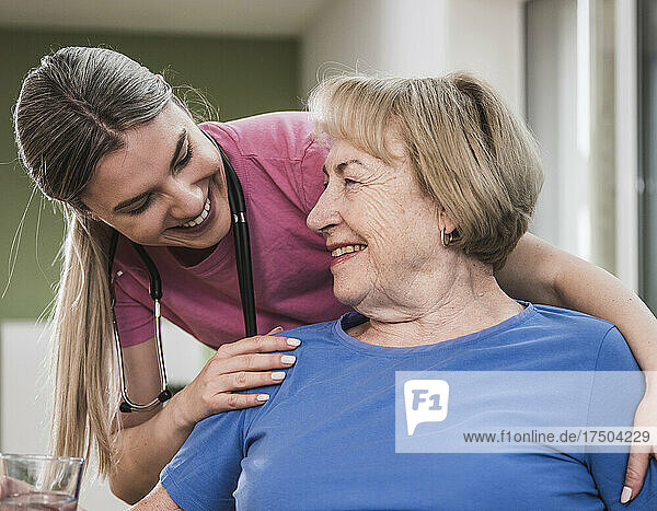 Junge Krankenschwester und behinderter Patient lächeln einander an