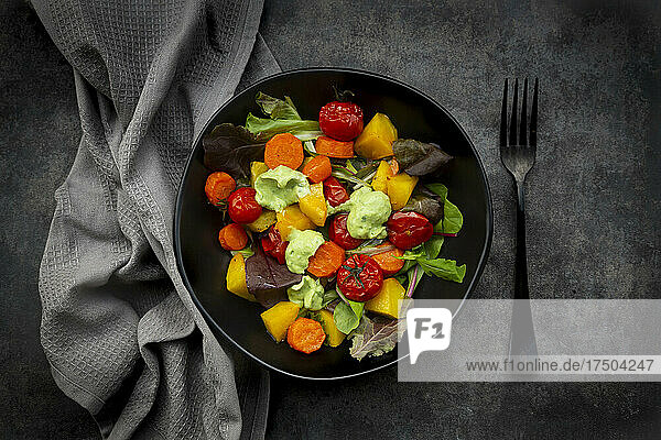 Studio shot of bowl of vegan salad with baked vegetables