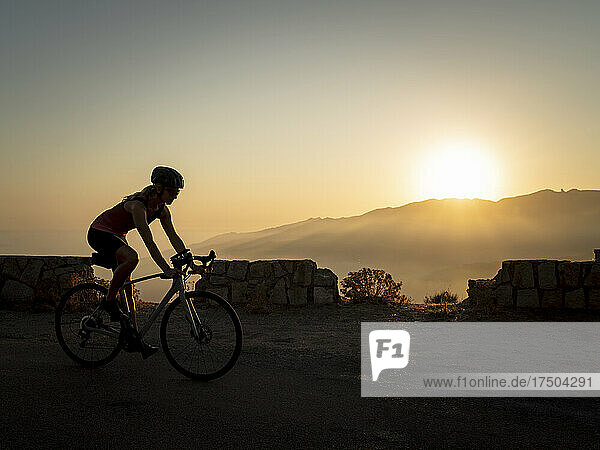 Sportswoman riding mountain bike at sunset