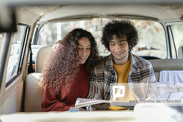 Smiling couple reading man in campervan on weekend