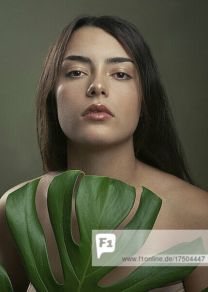 Shirtless young woman with monstera leaf