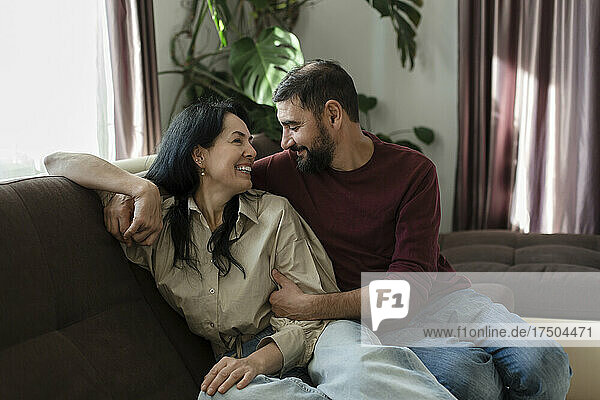 Lächelnde Frau sitzt mit Mann auf dem Sofa
