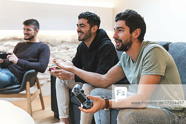 Excited friends playing video game together at home