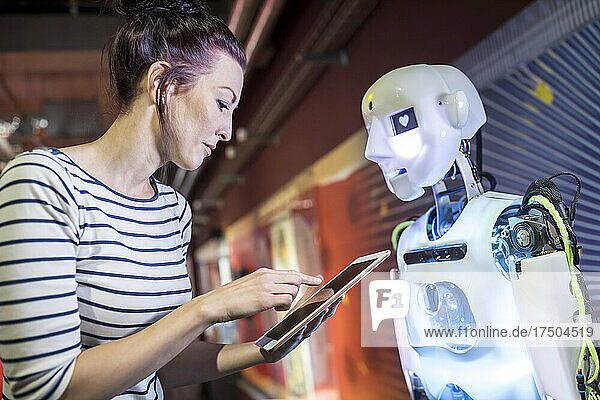 Technician programming human robot through tablet PC at workshop