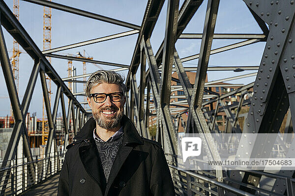 Smiling businessman wearing eyeglasses on bridge