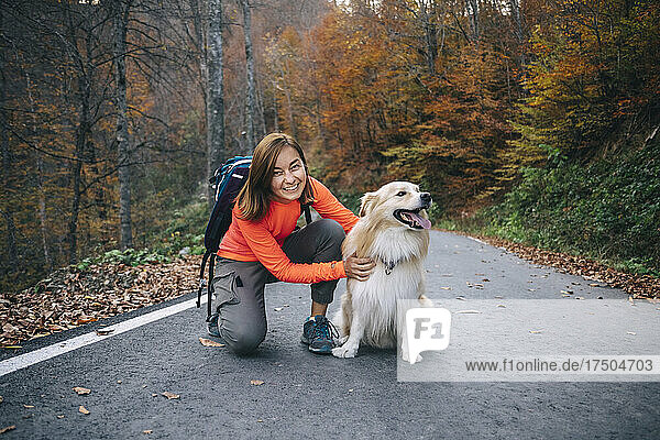 Smiling woman kneeling with dog on road